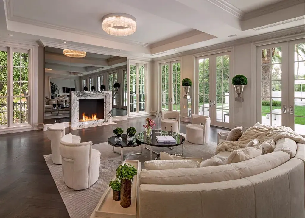 Bright luxury living room with a marble fireplace and garden doors, staged for sale